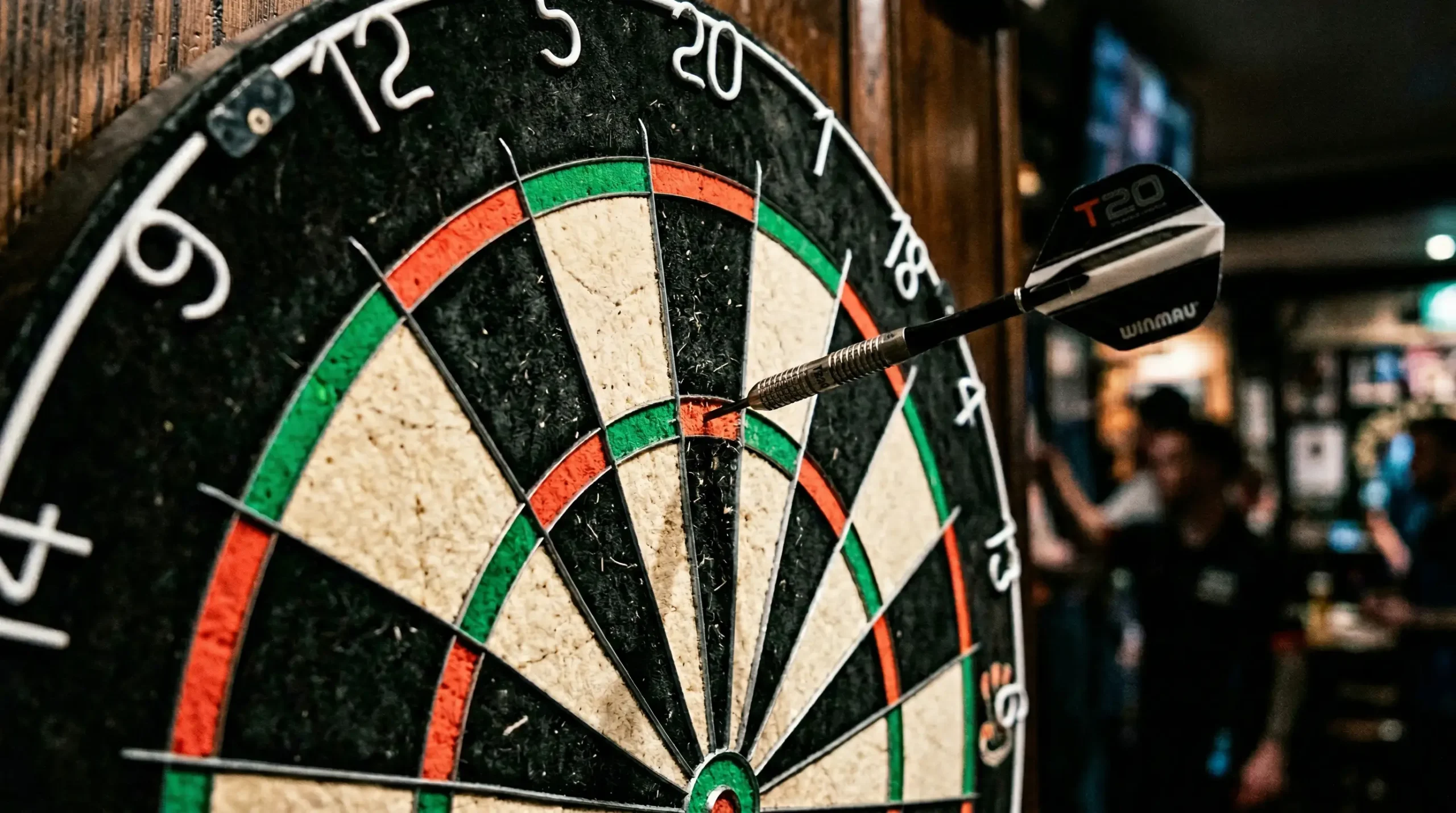Dartbord met pijl in triple 20 sector, spelregels darten uitgelegd